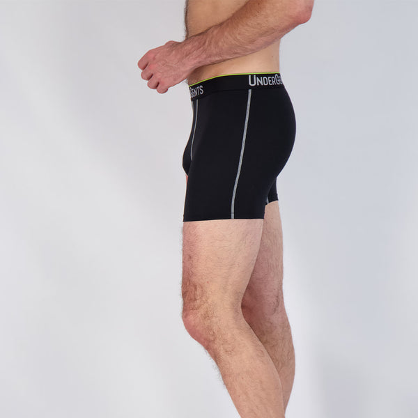 side view of 4.5 inch black boxer brief on white model who is thin. he feels the comfort of the leg skim instead of a leg squeeze