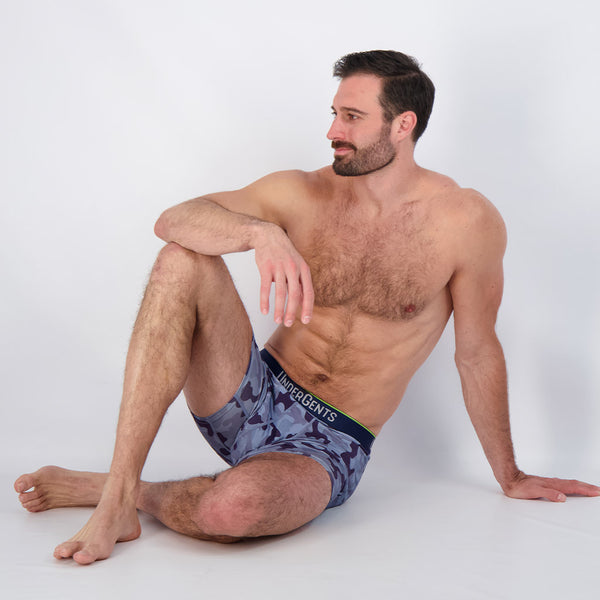 model wearing undergents blue camo boxer brief sitting down in perfect comfort. highest rated men's underwear on earth.